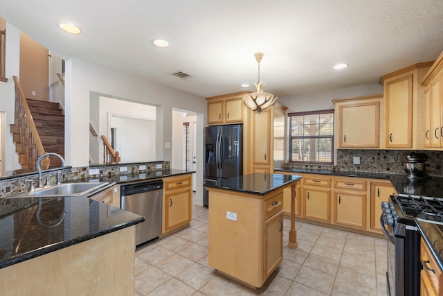 kitchen with sink, a center island, hanging light fixtures, appliances with stainless steel finishes, and dark stone counters