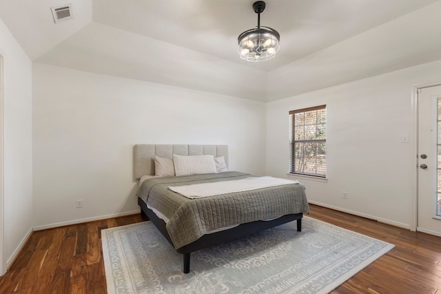 bedroom with lofted ceiling, dark hardwood / wood-style floors, and a raised ceiling