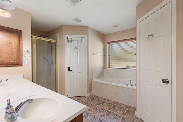 bathroom featuring independent shower and bath, vanity, and a textured ceiling