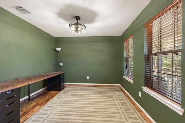 unfurnished office featuring wood-type flooring and a textured ceiling