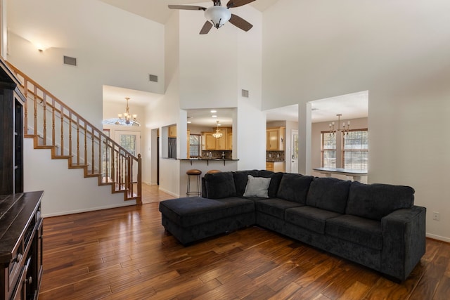 living room with a towering ceiling, ceiling fan with notable chandelier, and dark hardwood / wood-style floors