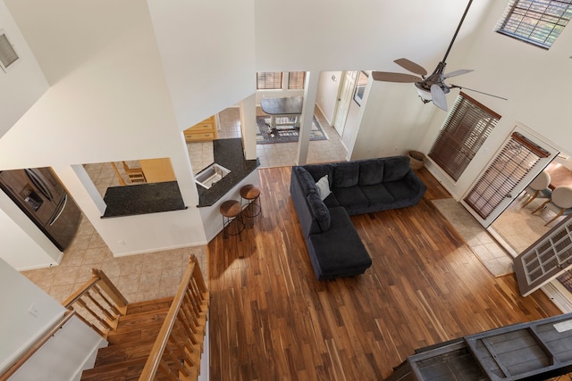 living room with a towering ceiling, wood-type flooring, and ceiling fan