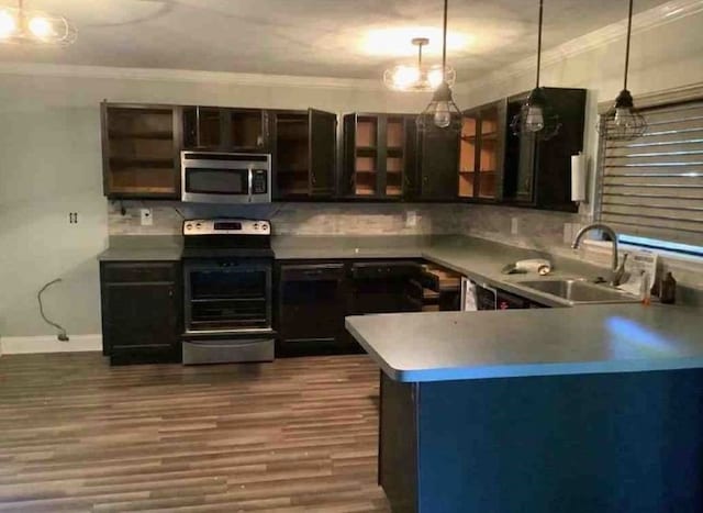 kitchen with appliances with stainless steel finishes, decorative light fixtures, sink, kitchen peninsula, and dark wood-type flooring