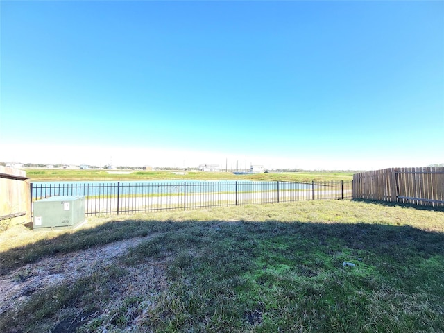 view of yard featuring a water view and a fenced backyard