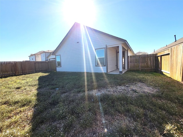 rear view of property with a fenced backyard and a lawn