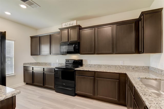 kitchen featuring light stone countertops, dark brown cabinets, black appliances, and light hardwood / wood-style floors