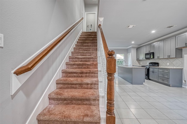 stairs with sink, tile patterned floors, and ornamental molding