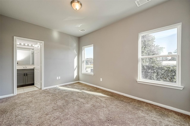 unfurnished bedroom featuring light colored carpet and connected bathroom