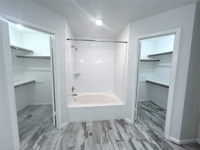 bathroom with hardwood / wood-style floors, a textured ceiling, and tiled shower / bath