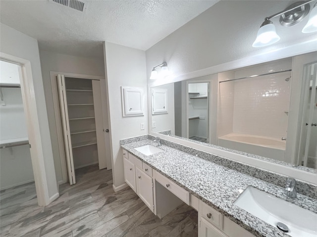 bathroom with vanity, hardwood / wood-style flooring, bathing tub / shower combination, and a textured ceiling