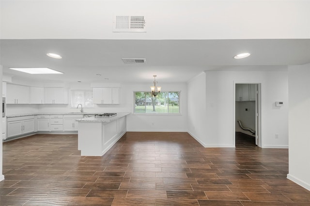 kitchen featuring decorative light fixtures, white cabinetry, a chandelier, kitchen peninsula, and light stone countertops