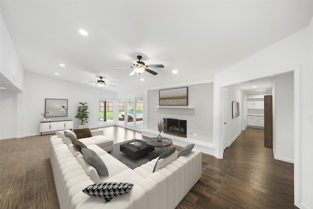 living room with vaulted ceiling, a large fireplace, ceiling fan, and dark hardwood / wood-style floors