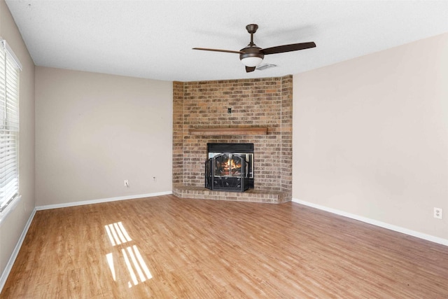 unfurnished living room featuring hardwood / wood-style flooring, a fireplace, a textured ceiling, and ceiling fan