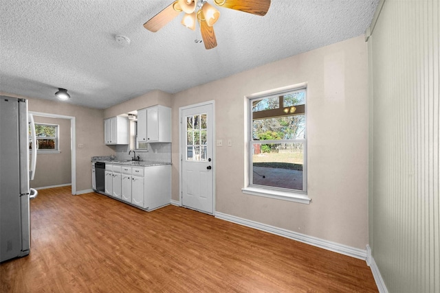 kitchen with plenty of natural light, light hardwood / wood-style floors, white cabinets, and appliances with stainless steel finishes