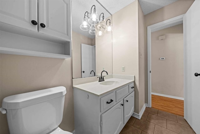 bathroom featuring tile patterned flooring, vanity, a notable chandelier, a textured ceiling, and toilet