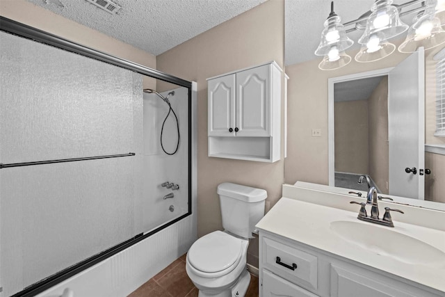 full bathroom featuring tile patterned flooring, bath / shower combo with glass door, vanity, a textured ceiling, and toilet