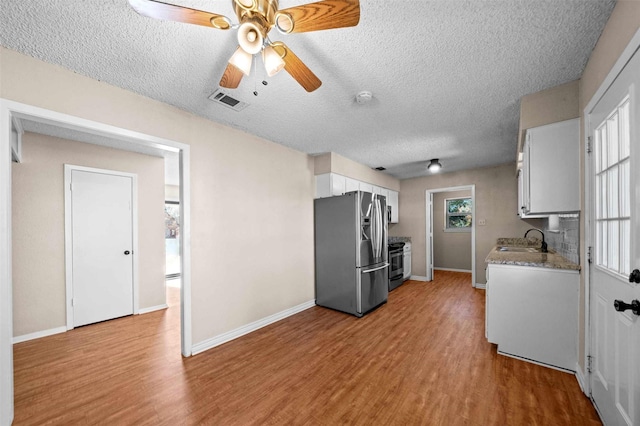 kitchen featuring sink, white cabinetry, stainless steel appliances, light hardwood / wood-style floors, and a textured ceiling