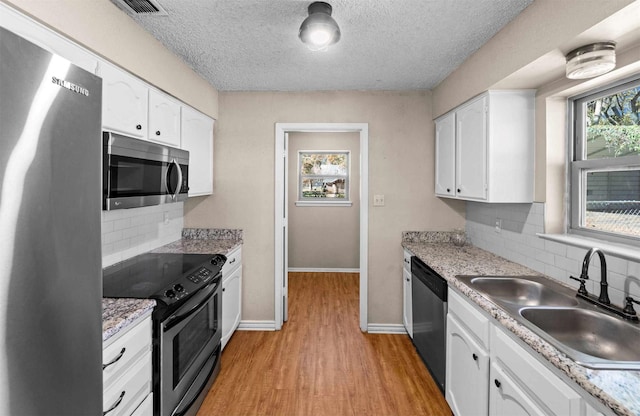 kitchen with sink, tasteful backsplash, a textured ceiling, stainless steel appliances, and white cabinets