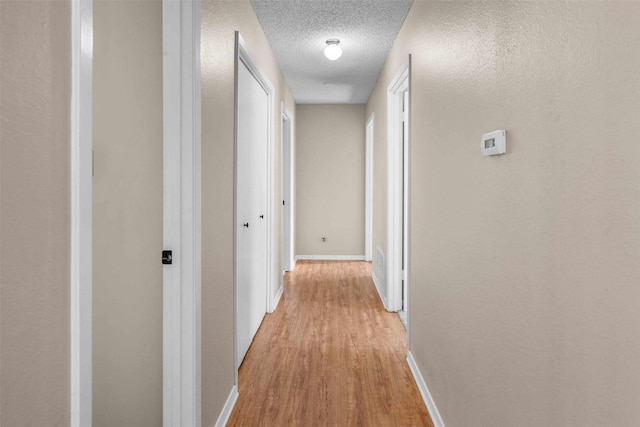 hallway featuring a textured ceiling and light wood-type flooring