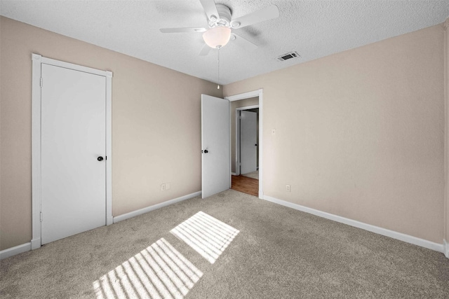 unfurnished bedroom with ceiling fan, light colored carpet, and a textured ceiling