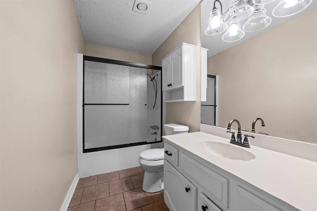 full bathroom with tile patterned flooring, bath / shower combo with glass door, vanity, a textured ceiling, and toilet