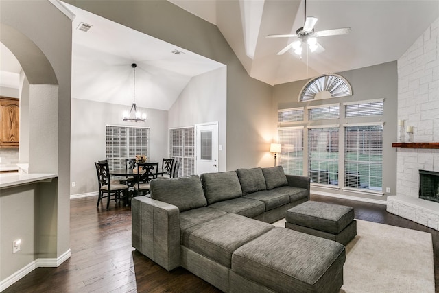 living room featuring lofted ceiling, dark hardwood / wood-style floors, ceiling fan with notable chandelier, and a fireplace