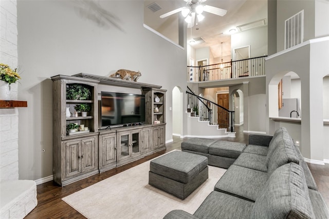 living room with dark wood-type flooring, ceiling fan, and a high ceiling