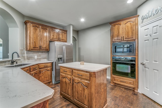 kitchen with built in microwave, stainless steel refrigerator with ice dispenser, a center island, black oven, and backsplash