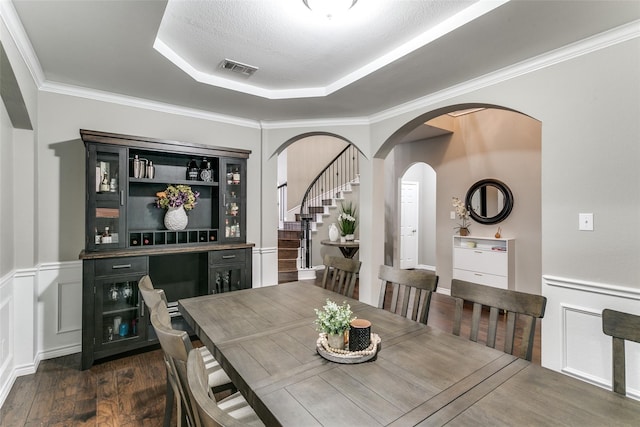 dining area with crown molding, dark hardwood / wood-style floors, a raised ceiling, and a textured ceiling