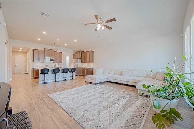 living room with light hardwood / wood-style floors and ceiling fan