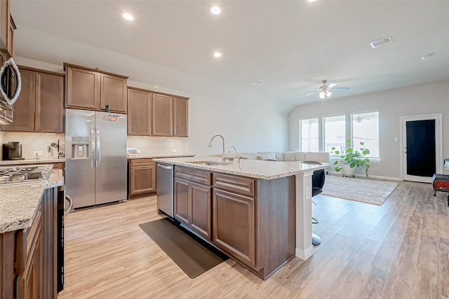 kitchen featuring stainless steel appliances, an island with sink, sink, and light hardwood / wood-style floors