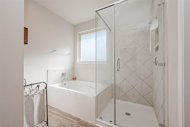 bathroom with independent shower and bath and hardwood / wood-style floors