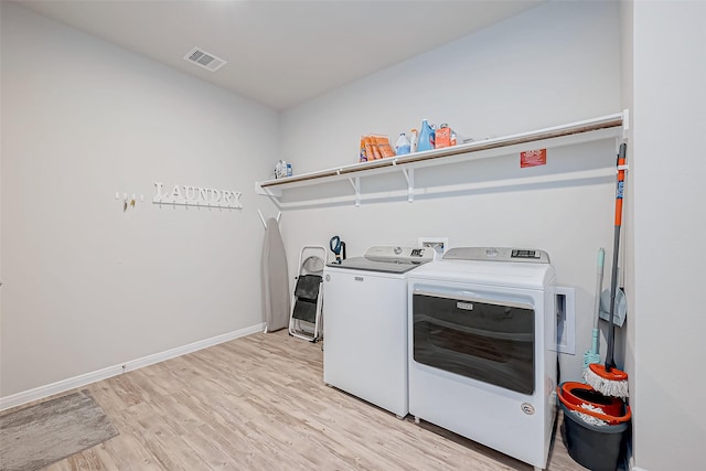 laundry room featuring washing machine and clothes dryer and light wood-type flooring