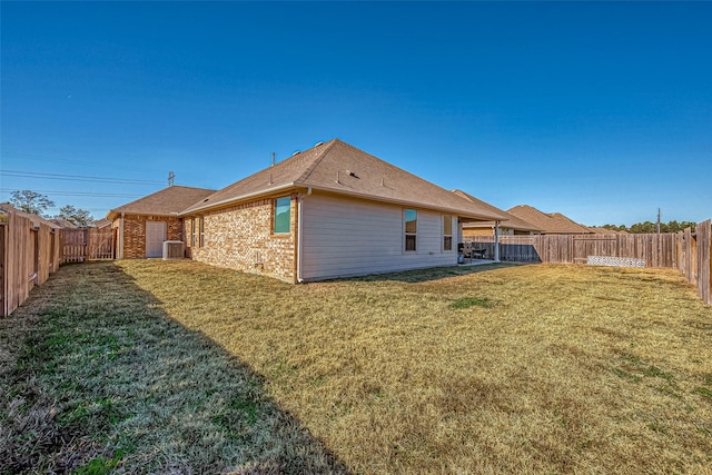 back of property featuring central AC and a yard