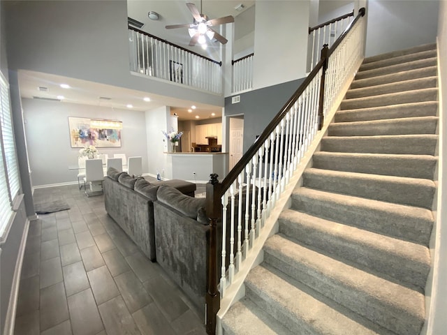 stairway featuring ceiling fan and a high ceiling