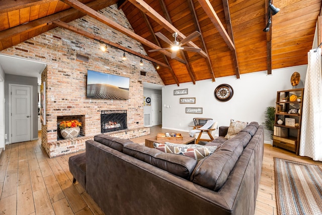 living room featuring high vaulted ceiling, wooden ceiling, ceiling fan, a fireplace, and light hardwood / wood-style floors