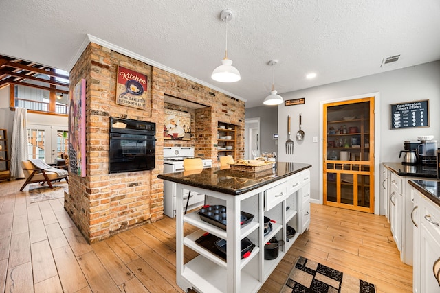 kitchen with light hardwood / wood-style flooring, range, hanging light fixtures, white cabinets, and oven