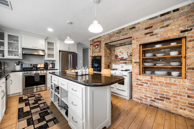 kitchen featuring white cabinetry, appliances with stainless steel finishes, range hood, and a kitchen island