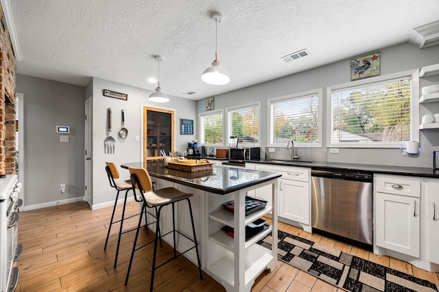 kitchen featuring sink, appliances with stainless steel finishes, hanging light fixtures, a center island, and white cabinets