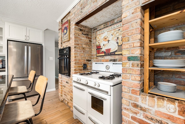 kitchen with a textured ceiling, stainless steel refrigerator, oven, range with two ovens, and white cabinets