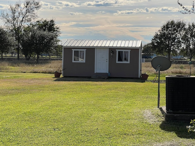 view of outdoor structure with central AC and a lawn