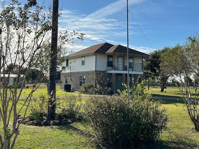 view of home's exterior featuring a balcony and a lawn