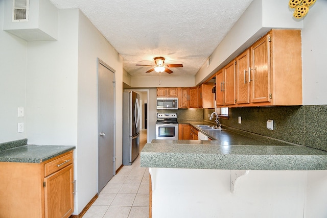 kitchen with light tile patterned flooring, appliances with stainless steel finishes, sink, decorative backsplash, and kitchen peninsula