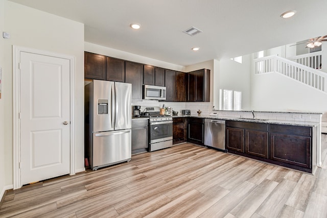 kitchen featuring sink, light hardwood / wood-style flooring, appliances with stainless steel finishes, dark brown cabinetry, and light stone counters