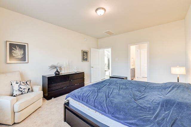 bedroom with ensuite bath and light carpet