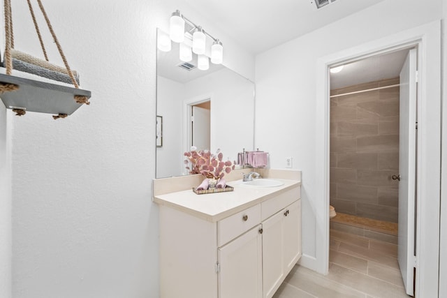 bathroom featuring vanity, tiled shower, and toilet