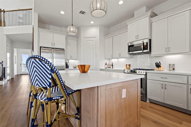 kitchen with stainless steel appliances, white cabinetry, a kitchen island, and pendant lighting