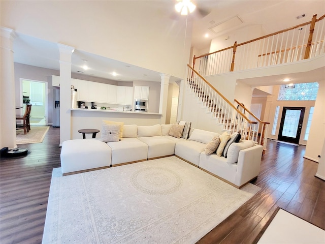 living room featuring hardwood / wood-style flooring, a towering ceiling, and decorative columns