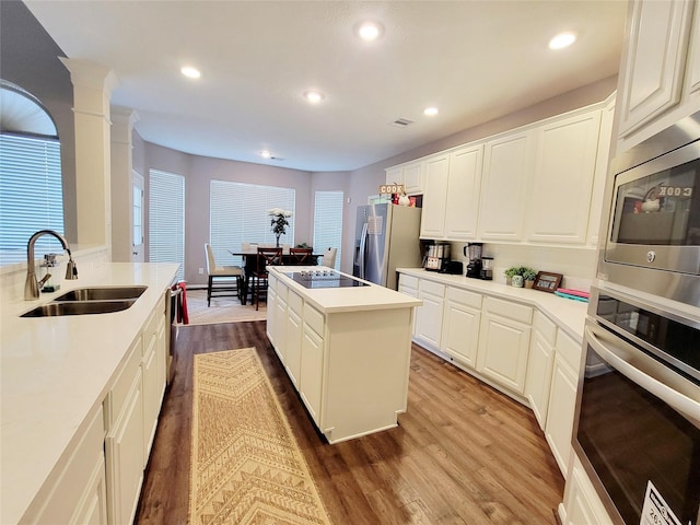 kitchen with white cabinetry, appliances with stainless steel finishes, sink, and a center island