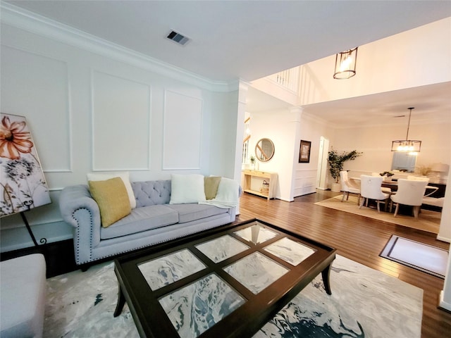 living room featuring crown molding, wood-type flooring, and ornate columns